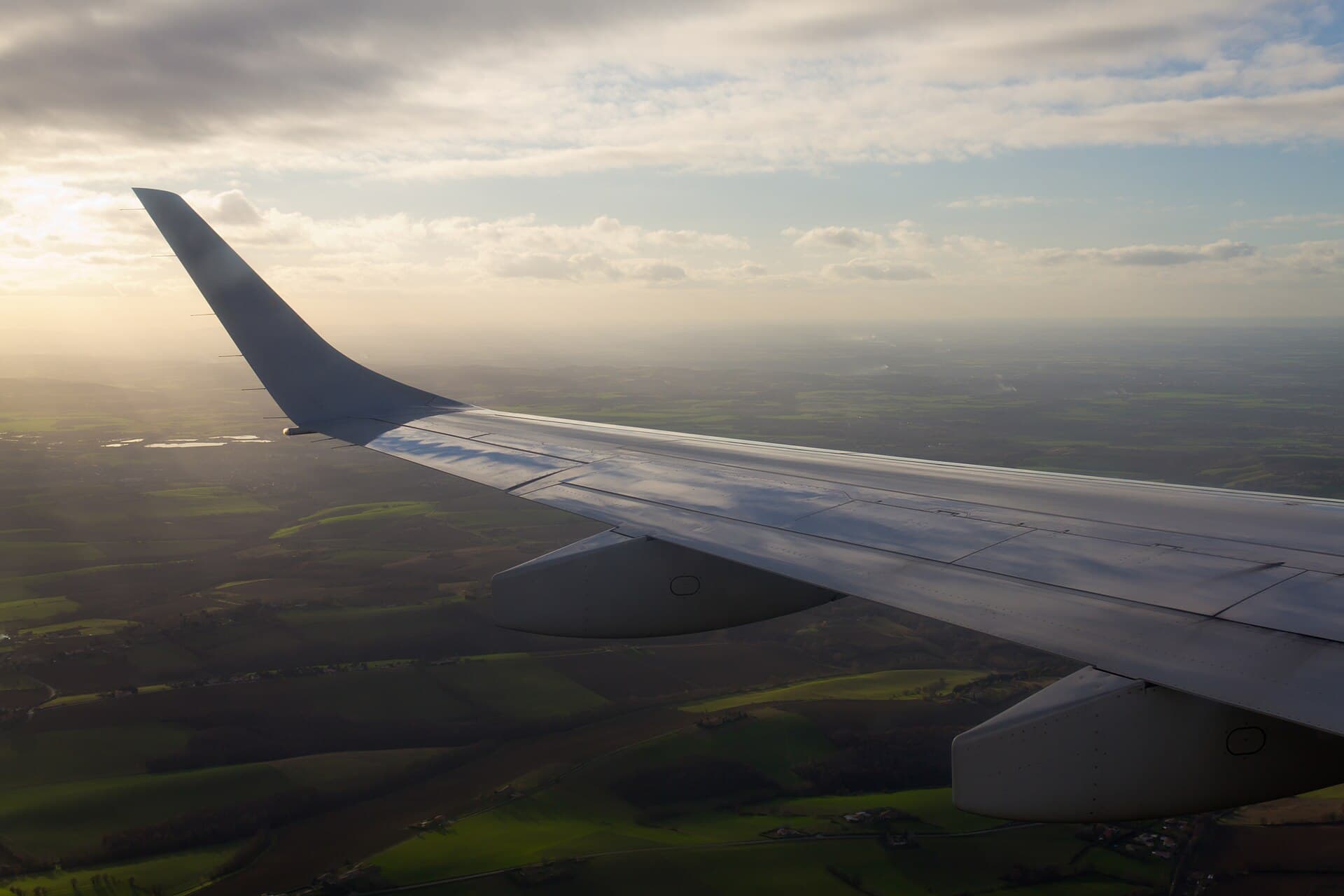 An aircraft wing and upturned winglet seen from a cabin window at sunset