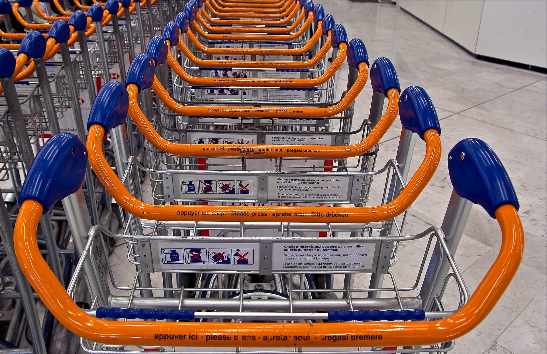 A row of airport luggage trolleys lined up in a terminal