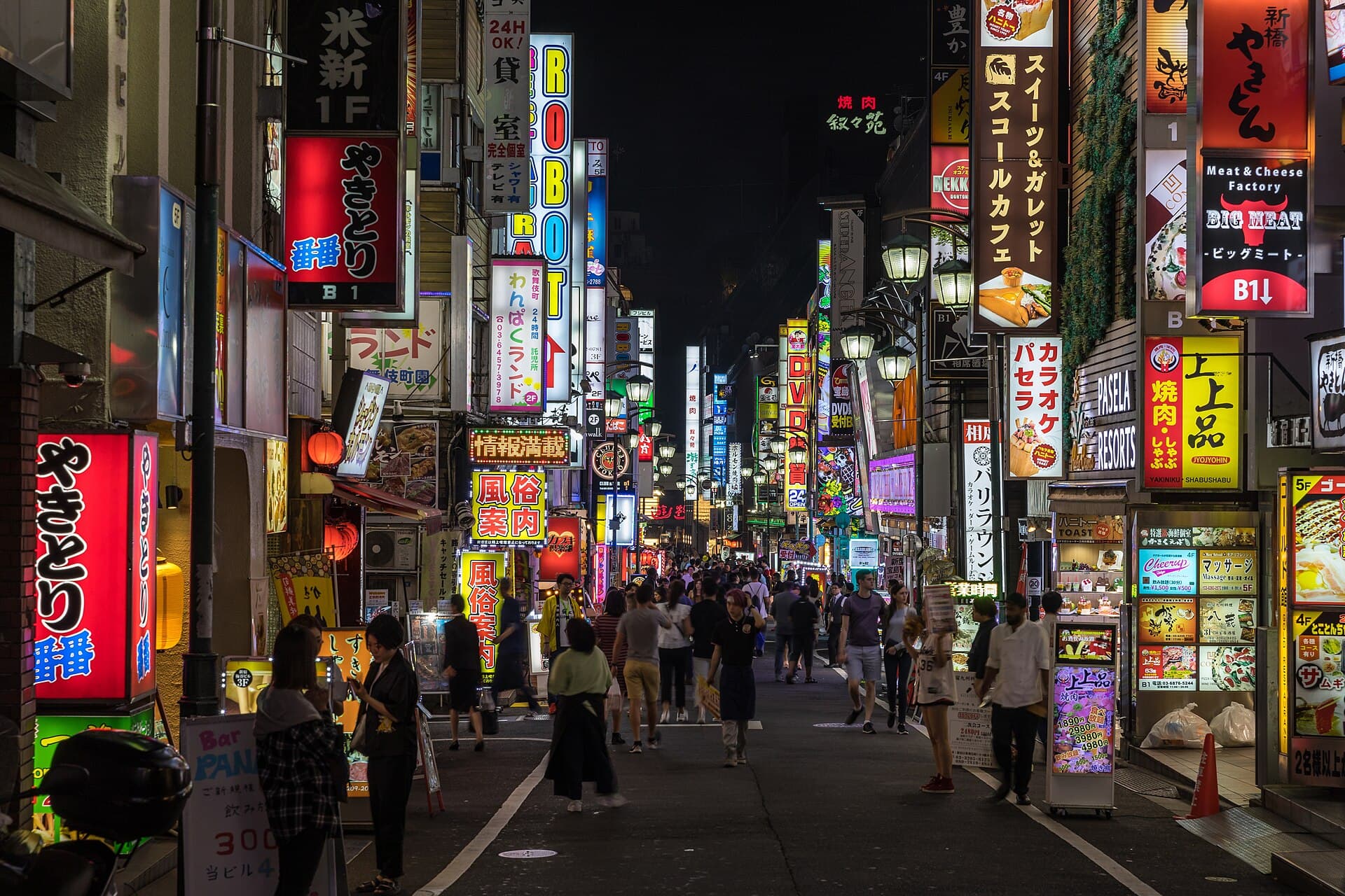 Colourful neon signs above a busy street in Kabukichō, Shinjuku, Tokyo, at night